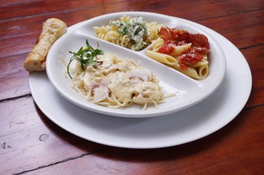 Üç çeşit pişmiş makarna ile beyaz bir tabak.