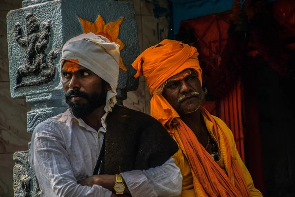 Foto de 40 a 60 ancianos grupo sacerdote indio, con paños de color blanco y azafrán y turbante, de pie cerca de pilar del templo en Mailapur, Karnataka. — Foto de Stock