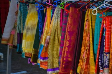Hint dükkanında askılarda asılı renkli sari koleksiyonu.