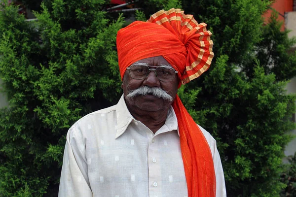 オレンジ色のターバンを身に着けている古いインドの祖父と写真のポーズを与える — ストック写真