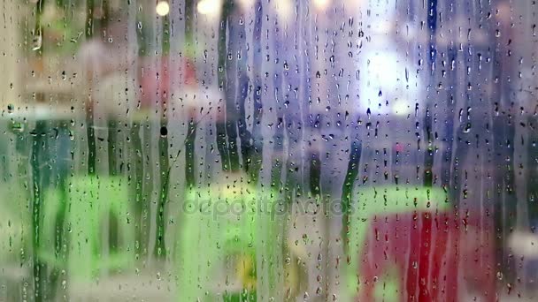 Water druppels glijden neer op winkel vensterglas — Stockvideo