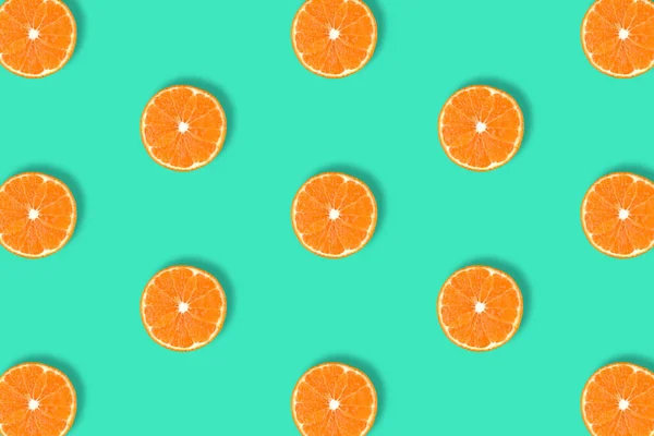 Fruit pattern of fresh mandarin slices on blue background.