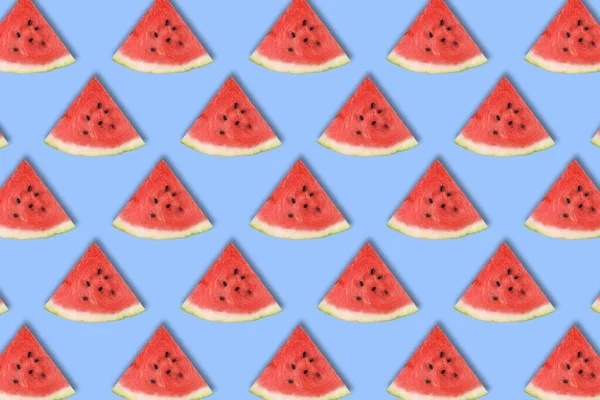 Flat lay of watermelon slices on blue background.
