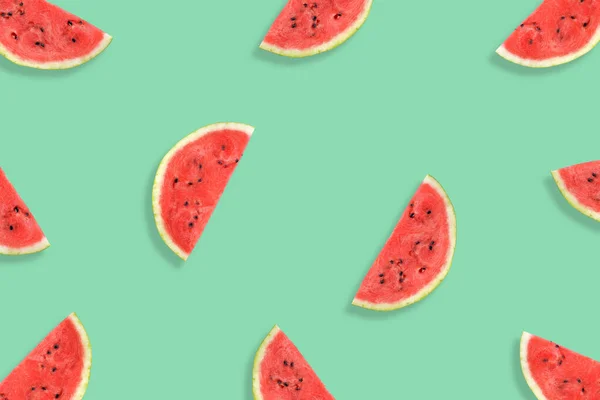 Flat lay of watermelon half slices on mint background. Watermelon pattern.