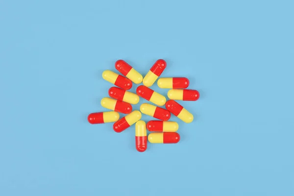 Yellow and red medical capsules on blue background.