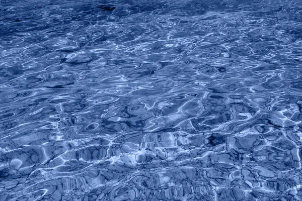 Tengeri víz háttér. Hullámok a kék átlátszó víz a tengeren, napfény visszaverődés. — Stock Fotó