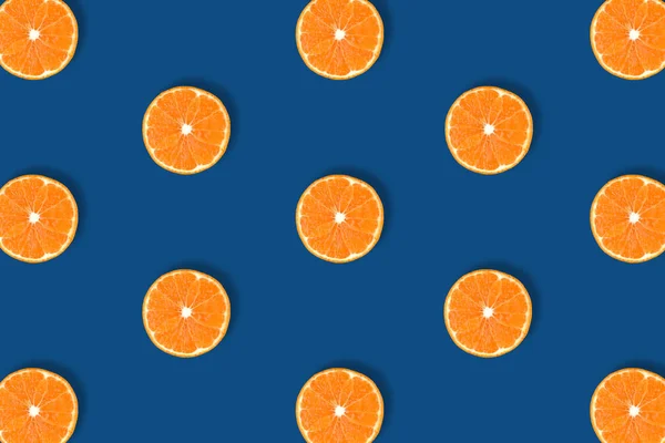 Fruit pattern of fresh bright orange citrus slices isolated on classic blue background.