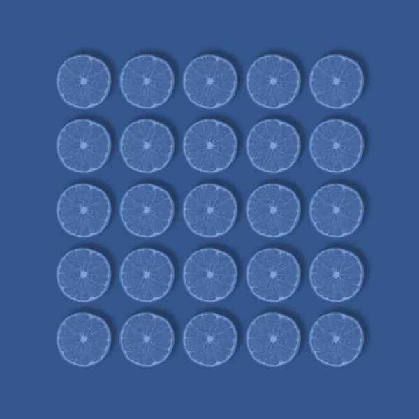 Μοτίβο φρούτων από φρέσκες φέτες μανταρινιού τονισμένες σε μπλε, απομονωμένες σε βαθύ μπλε φόντο. Επίπεδο lay, πάνω όψη — Φωτογραφία Αρχείου
