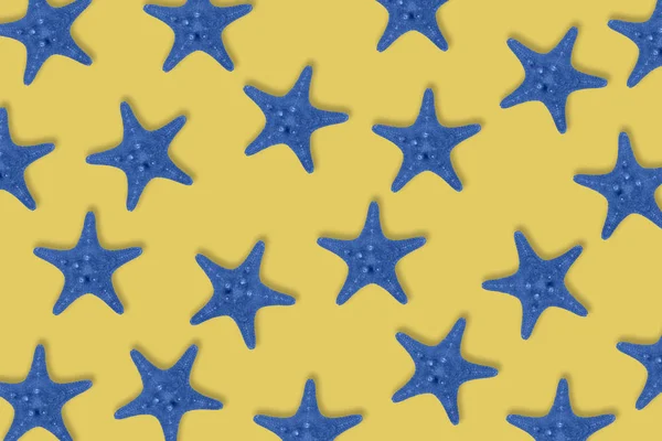 Dried toned in blue sea star fish pattern on yellow background. — Stockfoto