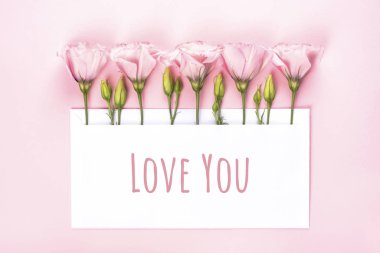 Bayılırım pankarta. Açık pembe arkaplan üzerinde boş kart ile Eustoma çiçek düzenleme.