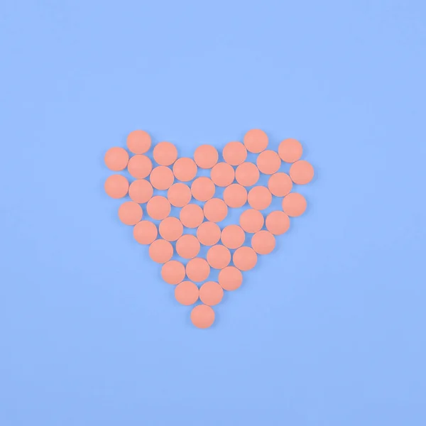Medical background or banner. Pink Pills in form of heart on blue background. — 스톡 사진