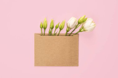 Parti ya da düğün davetiyesi. Çiçekli Eustoma çiçeği aranjmanı ve pembe arka planda boş kahverengi kart. Sevgililer Günü için modaya uygun pankart, Uluslararası Kadınlar Günü.