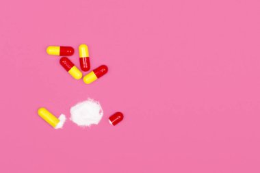 Tıbbi geçmişi var. Pembe arka planda açık kırmızı ve sarı kapsül hapları. Fuşya arkaplanına yayılmış kapsüller için kopya alanı.