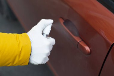 Kadın elleri, el dezenfektanı ile arabanın kapı kolunu dezenfekte eder. Koronavirüs salgını önlem önlemleri kavramını yayıyor.