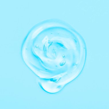Hyaluronik asit serumunu kapat. Temiz sıvı jel damlası ya da mavi arka planda izole edilmiş bir leke. Üst Manzara. Vücut ve yüz bakımı kozmetik konsepti. Serum dokusu.
