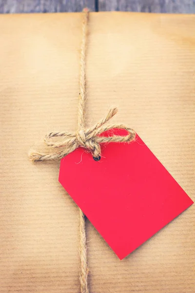 Dárek v kraftový papír s červenou kartu — Stock fotografie