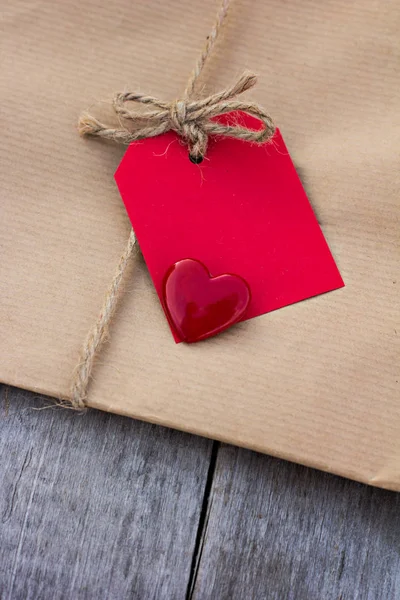 Dárek v sulfátového papíru s červenou kartu a srdce — Stock fotografie