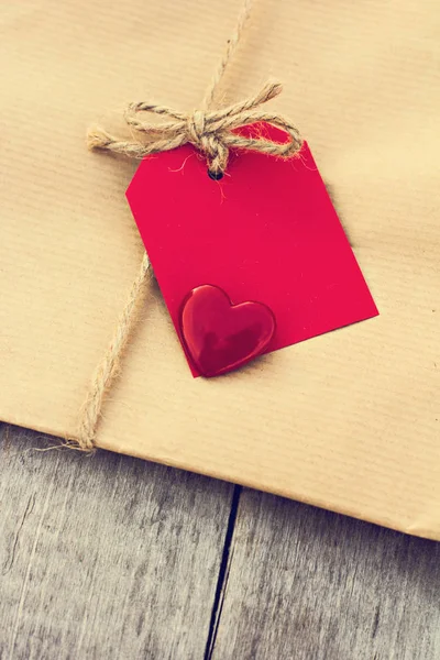 Prezent w papier pakowy z czerwoną kartkę i serca — Zdjęcie stockowe