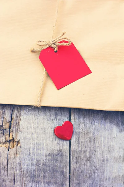 Подарок из крафтовой бумаги с красной карточкой и сердцем — стоковое фото