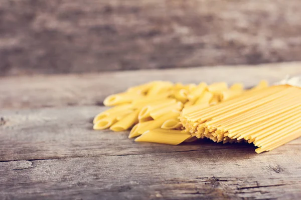 Macaroni, pasta, spaghetti on a wooden background.