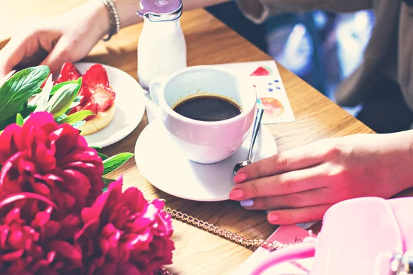 Een kopje koffie in een café en een girl's handen. — Stockfoto