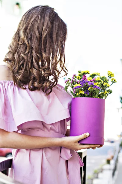 Mooi meisje houdt van een doos met bloemen in haar handen — Stockfoto