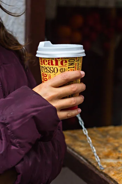 A paper cup with coffee in the hands of a girl.