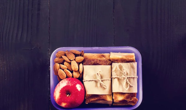 Snack to school, snack to work, lunch with you, pie. apple and nuts in a container.
