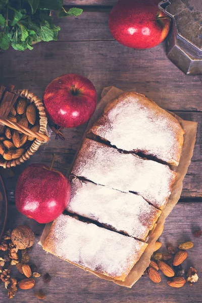 Ev yapımı elma strudel taze elma, tarçın ve pudra şekeri ile eski ahşap arka plan üzerinde hizmet dilimlenmiş. Yakın, karanlık rustik tarzı Apple strudel.