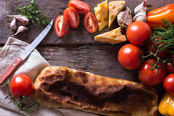 Ev yapımı tavuk, peynir ve eski bir ahşap masa üzerinde beyaz soslu sebze meyveli turta. Rustik tarzı.