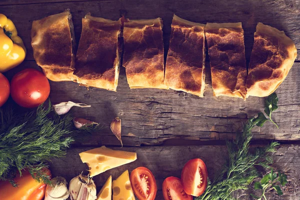 Ev yapımı tavuk, peynir ve eski bir ahşap masa üzerinde beyaz soslu sebze meyveli turta. Rustik tarzı.