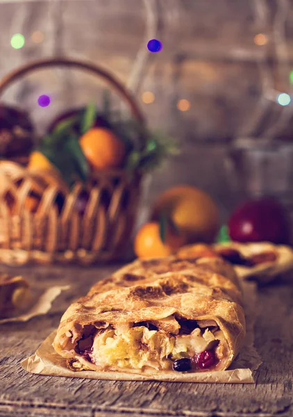 meyveli turta ve kış dekor. Apple strudel (pasta) kurutulmuş meyve, portakal, kızılcık, ceviz ve Noel dekorasyonu ile pudra şekeri. Kış dekor. Rustik tarzı.