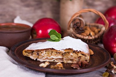 Ev yapımı elma strudel taze elma, tarçın ve pudra şekeri ile eski ahşap arka plan üzerinde hizmet dilimlenmiş. Yakın, karanlık rustik tarzı Apple strudel.