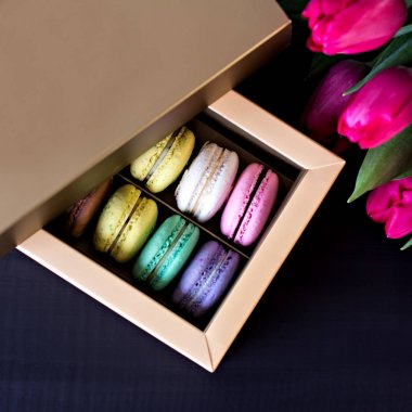 Bademli kurabiye kutusu ve bir buket laleler ve karanlık bir arka plan üzerinde metin için bir kart. 