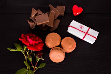 Çikolata macaroons, hediye ve karanlık bir arka plan üzerinde gül çiçek. 