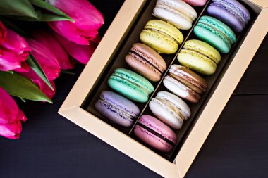 Bademli kurabiye kutusu ve bir buket laleler ve karanlık bir arka plan üzerinde metin için bir kart. 