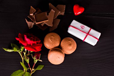 Çikolata macaroons, hediye ve karanlık bir arka plan üzerinde gül çiçek. 