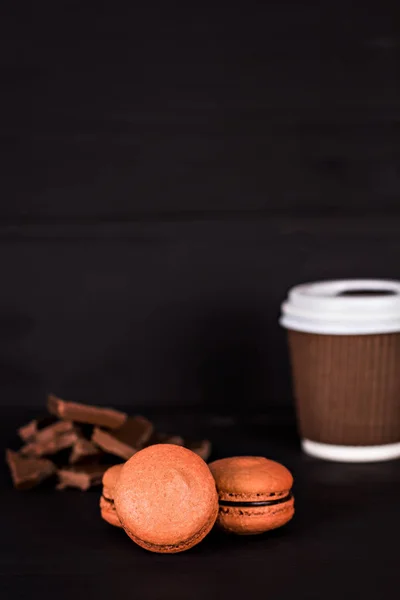 Macarrones de chocolate y una taza de papel con café — Foto de Stock