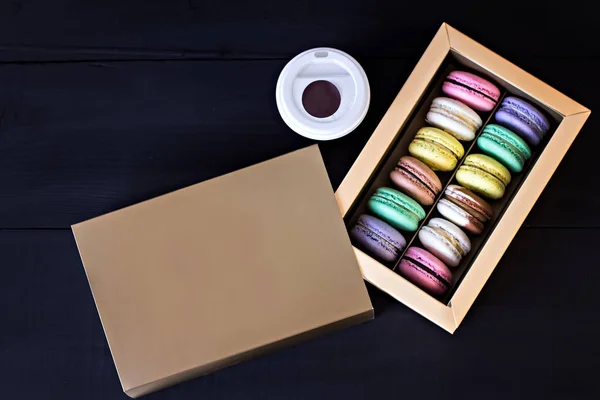 Box with macaroons and a bouquet of tulips and a card for your text on a dark background. — Stock Photo, Image