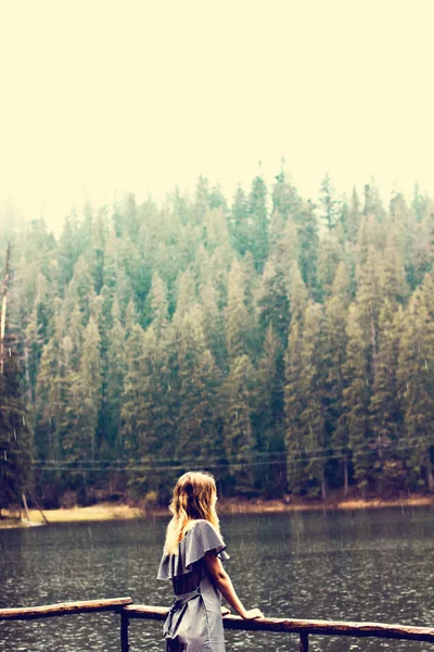 Das Mädchen steht am See im Regen. — Stockfoto