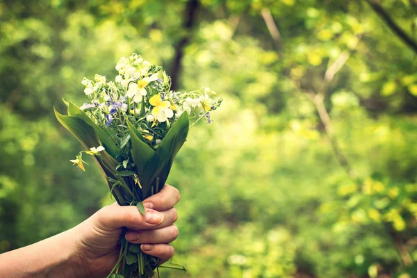 Un bouquet de lys de la vallée et de violettes de la forêt dans la main d'une femme . — Photo