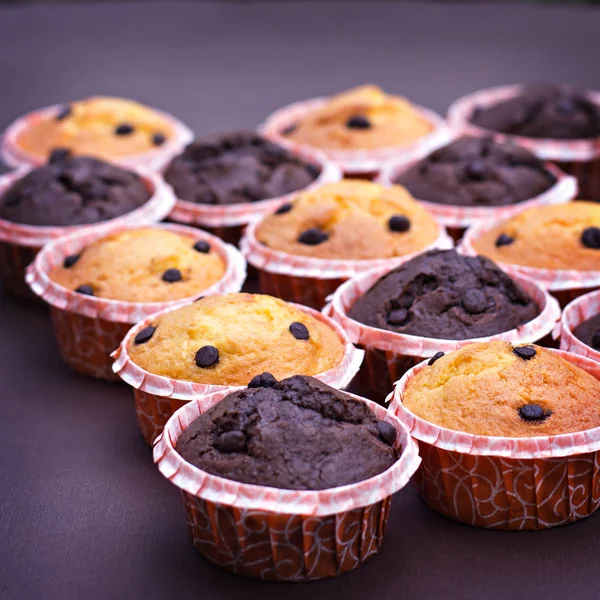 Gâteau au chocolat et cupcakes à la vanille avec des gouttes de chocolat sur la table . — Photo