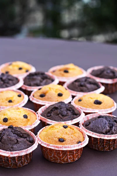 Torta al cioccolato e cupcake alla vaniglia con gocce di cioccolato sul tavolo . — Foto Stock
