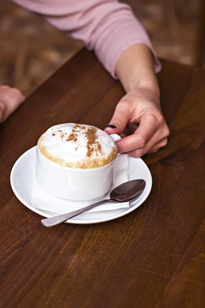 Female hands holding a cup of coffee - cappuccino. — Stock Photo, Image