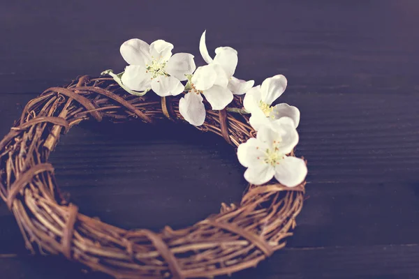 Corona con flores de primavera sobre un fondo de madera oscura . —  Fotos de Stock