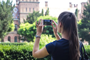 Bir kız bir fotoğraf tarihi bir binada bir cep telefonunda yapıyor.