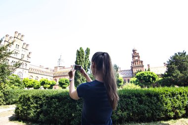 Bir kız bir fotoğraf tarihi bir binada bir cep telefonunda yapıyor.