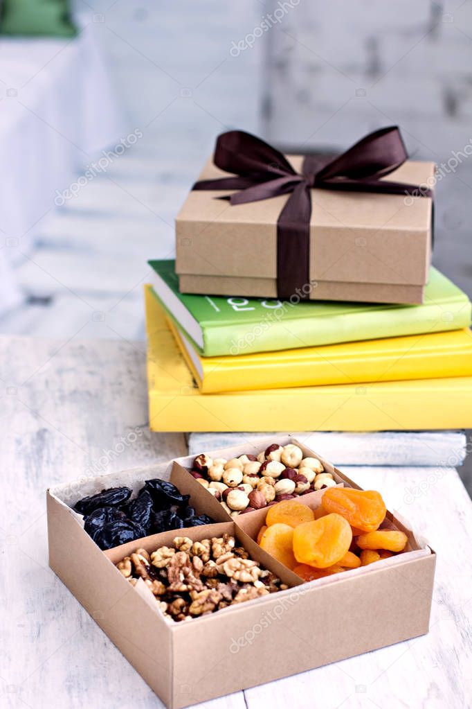 A box of nuts and dried fruits and a stack of books. 