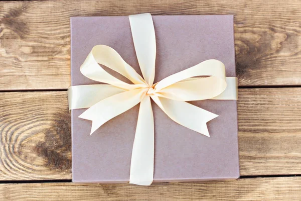 Gift. Craft box with a bow on wooden boards. — Stock Photo, Image