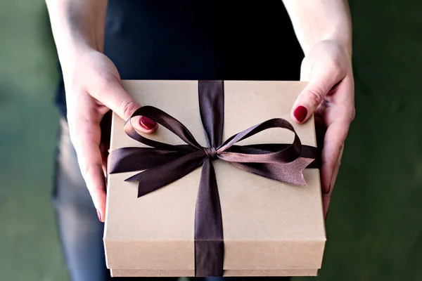 Las manos femeninas sostienen una caja hecha a mano con un regalo . — Foto de Stock